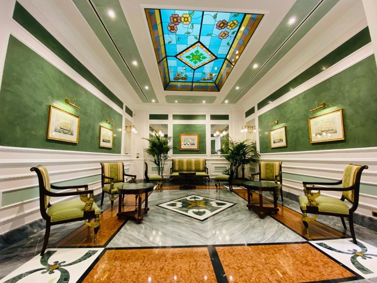 Hotel Bristol Palace Genoa Exterior photo The photo shows a well-decorated interior space, likely a lobby or reception area. The walls are painted a soft green, and the ceiling features a colorful stained glass design with geometric patterns. 

There are several elegant furnishings, includin
