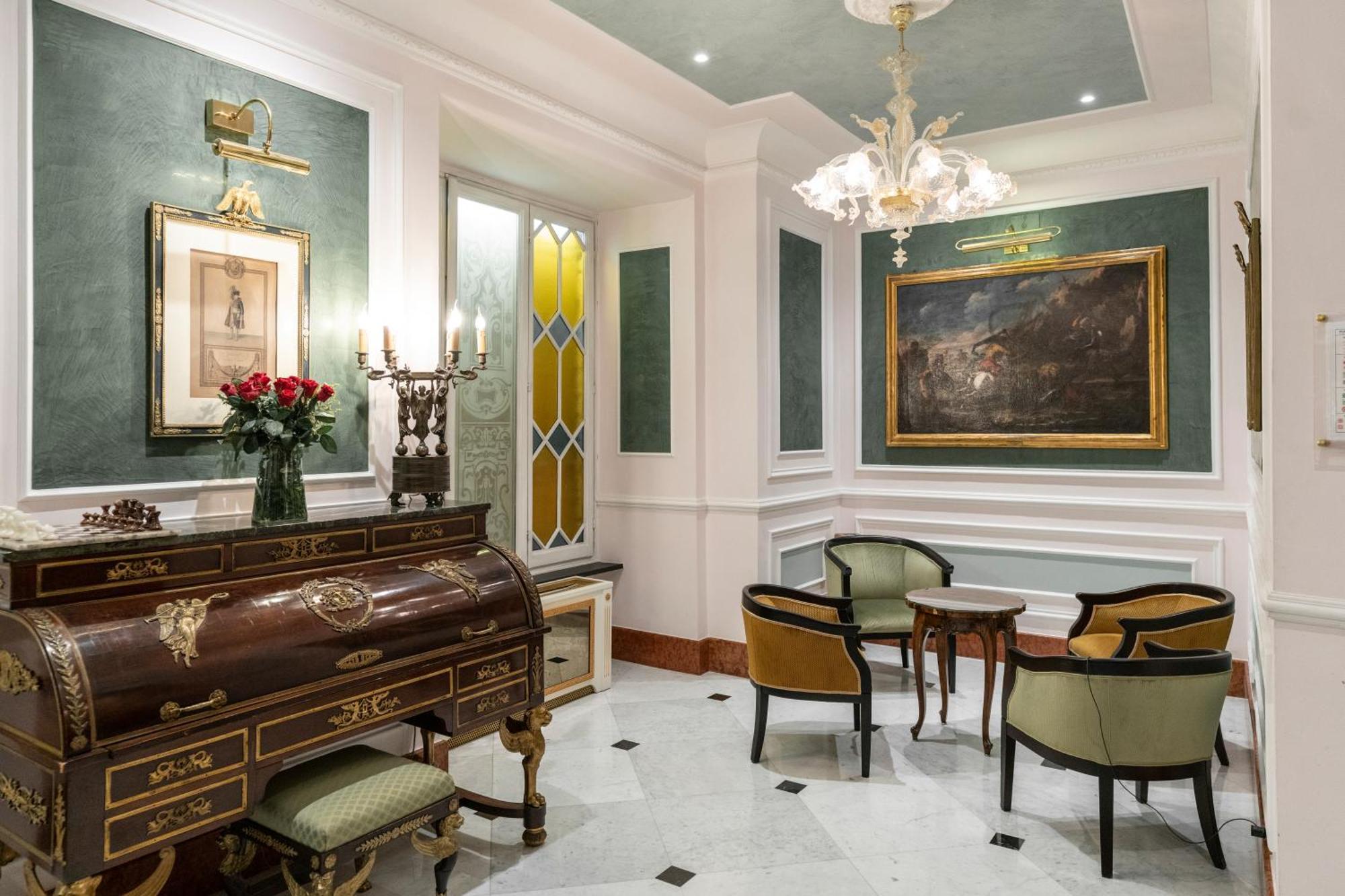 Hotel Bristol Palace Genoa Exterior photo The photo shows a beautifully decorated interior space that appears to be a small living or reception area. It features elegant furniture, including a wooden writing desk or chest with intricate designs and several chairs with a mix of colors. 

The 