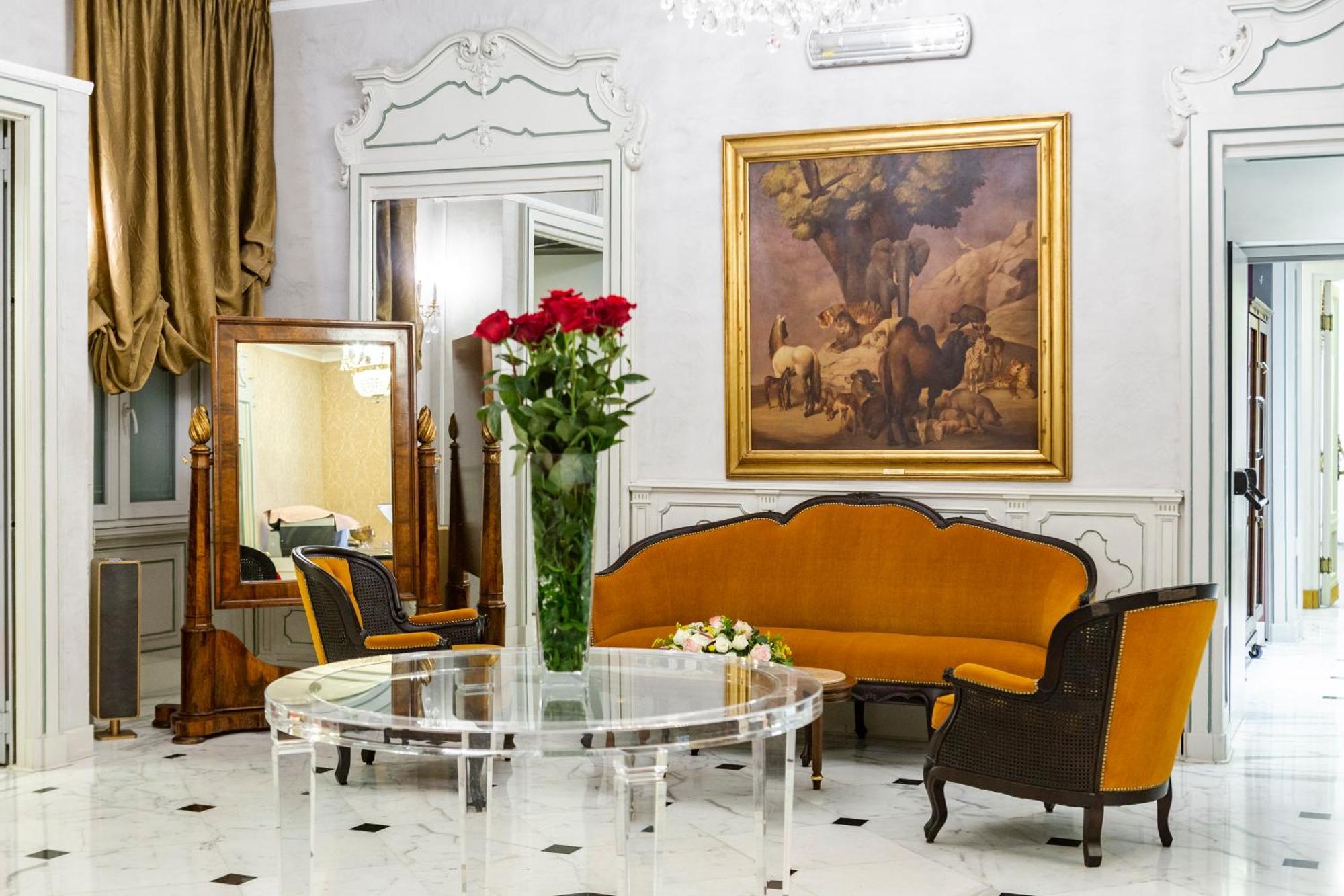 Hotel Bristol Palace Genoa Exterior photo The photo displays an elegant interior setting, likely a living room or reception area. Key features include:

- A round glass table placed in the center.
- An orange upholstered sofa with a curved design, complemented by matching chairs with dark wo