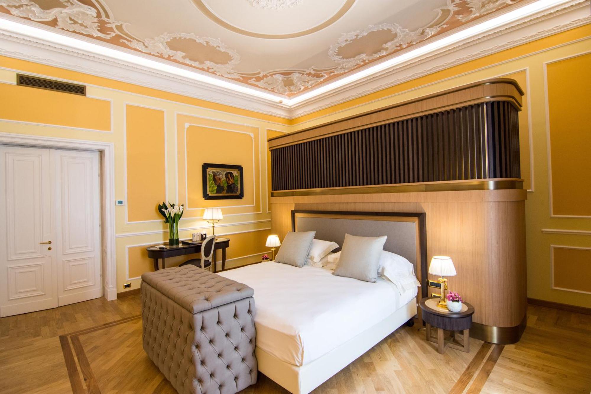 Hotel Bristol Palace Genoa Exterior photo The photo shows a beautifully arranged bedroom with elegant decor. The room features warm yellow walls, complemented by intricate molding and a decorative ceiling. In the center, there is a neatly made bed with light-colored bedding and two decorativ
