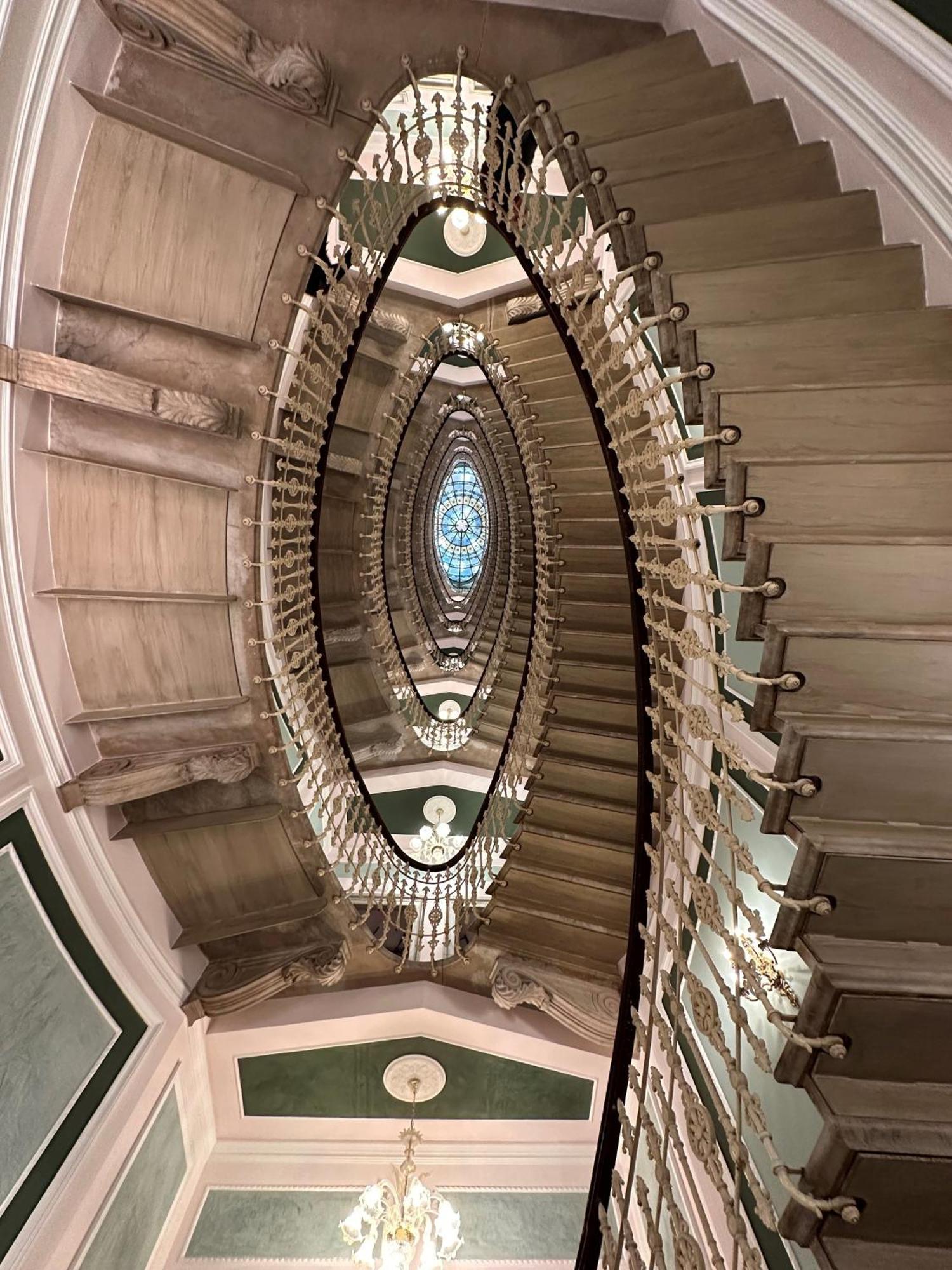 Hotel Bristol Palace Genoa Exterior photo The photo depicts a grand spiral staircase featuring an elegant design. The staircase is constructed with ornate railings and is surrounded by decorative details. At the center, there is a large, illuminated dome or skylight which adds a sense of ope