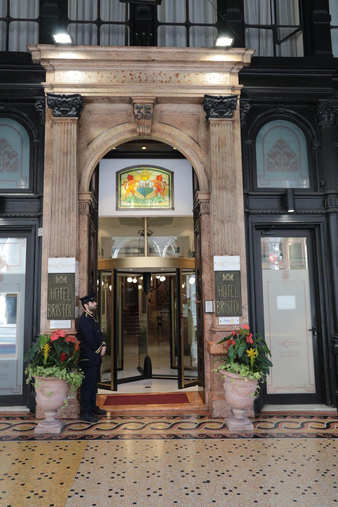 Hotel Bristol Palace Genoa Exterior photo The photo shows the entrance of a hotel, specifically the "Hotel Bristol." The entrance features an ornate archway with decorative elements. Above the main door, there is a stained glass window with colorful designs. To the sides of the entrance, the