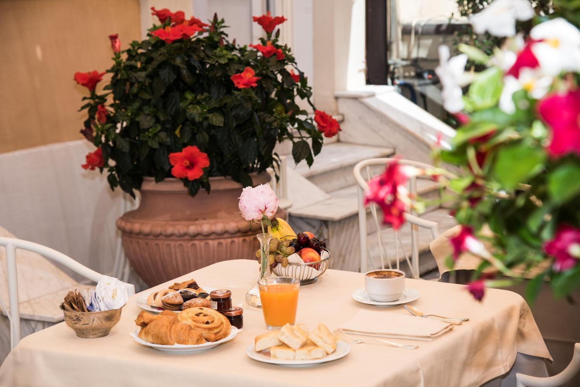 Hotel Bristol Palace Genoa Exterior photo The photo shows a charming breakfast setup on a table covered with a light-colored tablecloth. There is a variety of food items, including pastry items like croissants and sweet rolls, alongside some fruit. Also visible is a small glass of orange jui